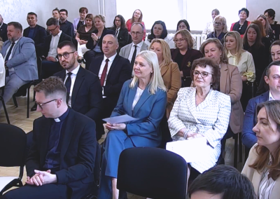 Widownia konferencji złożona z licznie zgromadzonych uczestników siedzących na krzesłach w sali szkoleniowej