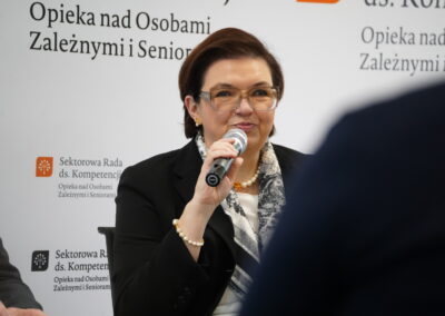 Ekspert mówi do mikrofonu podczas dyskusji o potrzebach kompetencyjnych w sektorze opieki
